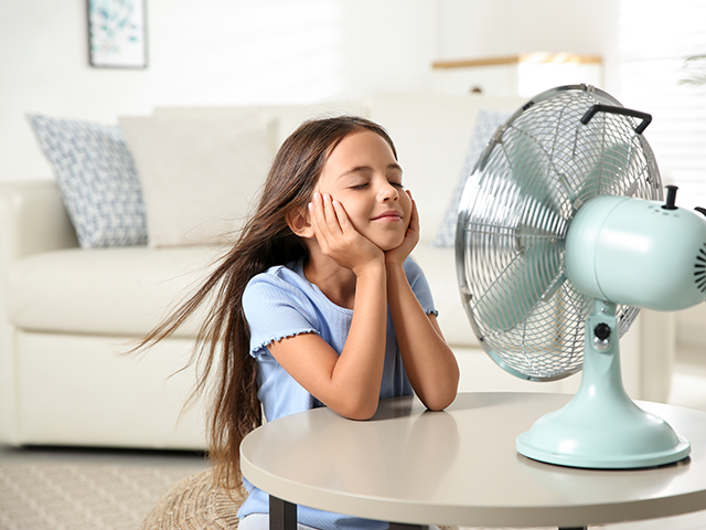 Νεαρό κορίτσι απολαμβάνει τον αέρα επιτραπέζιου ανεμιστήρα